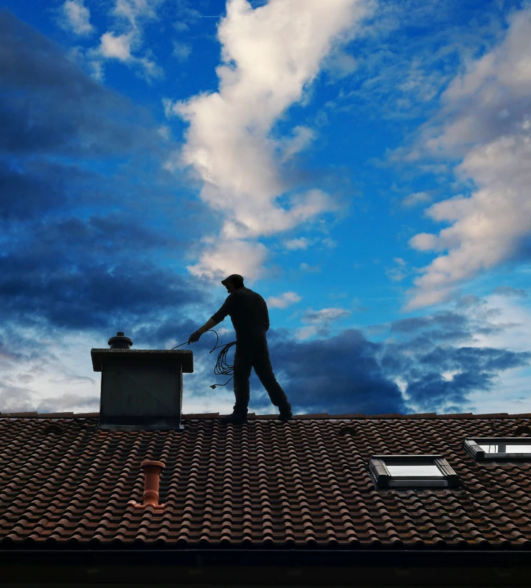 kominiarz na&nbsp;dachu i&nbsp;niebieskie niebo