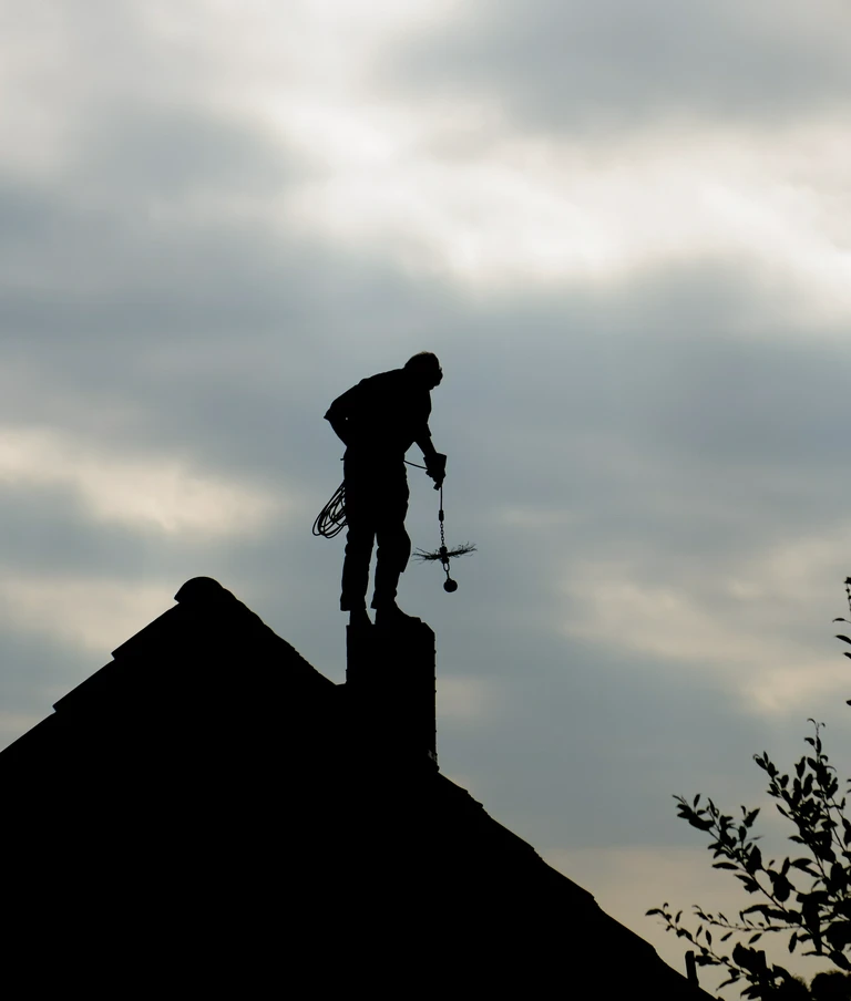 kominiarz na&nbsp;dachu po&nbsp;zmroku